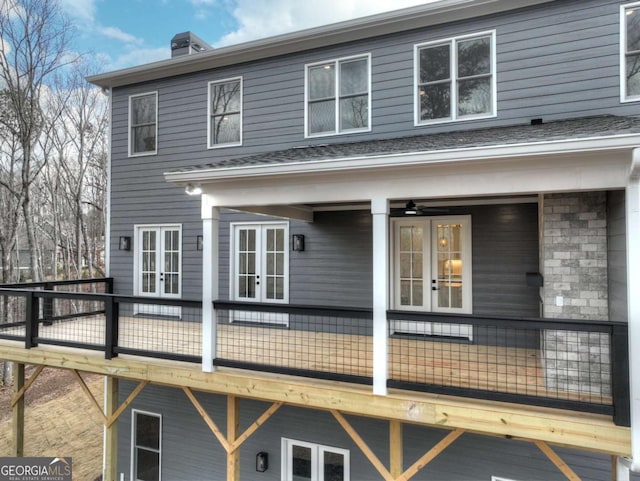 rear view of property featuring french doors, a chimney, and a deck