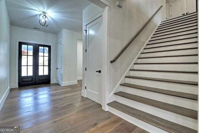 foyer entrance featuring stairway, baseboards, wood finished floors, and french doors