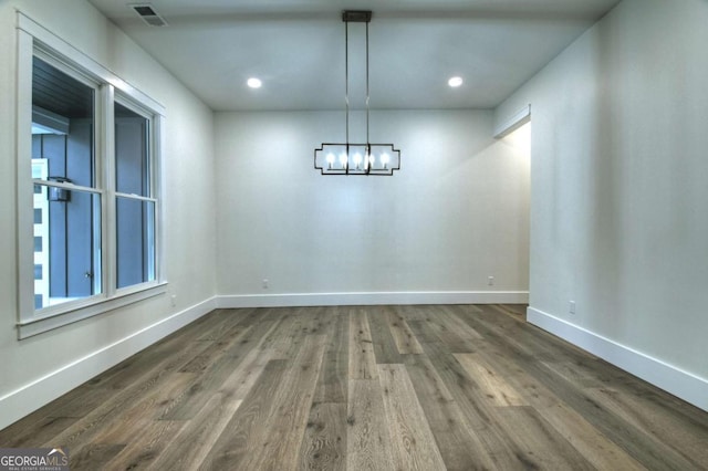 unfurnished dining area featuring dark wood finished floors, a notable chandelier, recessed lighting, and baseboards