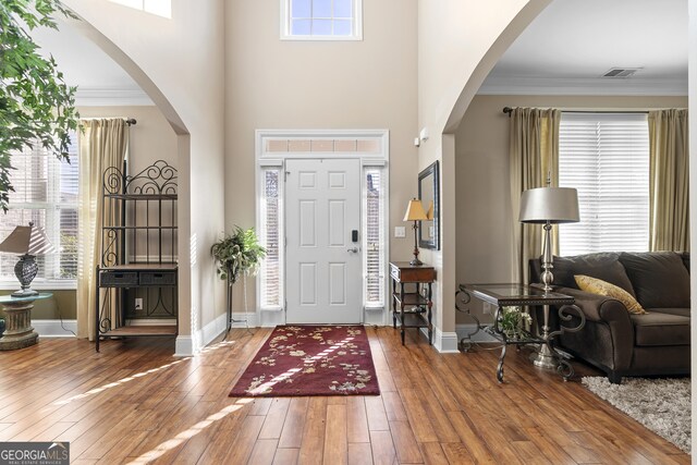 foyer entrance featuring dark hardwood / wood-style floors, crown molding, and a high ceiling