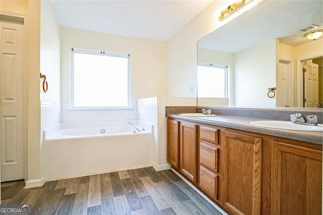 bathroom with a washtub, vanity, a healthy amount of sunlight, and hardwood / wood-style flooring