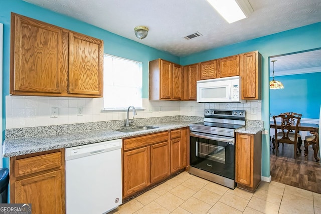 kitchen featuring light stone counters, white appliances, a textured ceiling, sink, and light tile patterned floors