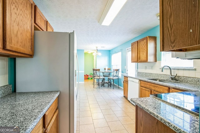 kitchen with white dishwasher, sink, stainless steel fridge, light tile patterned floors, and a textured ceiling