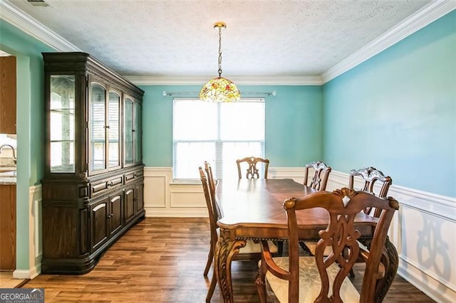 dining space featuring sink, hardwood / wood-style floors, a textured ceiling, and ornamental molding