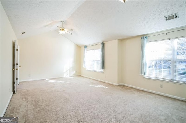 carpeted spare room featuring a textured ceiling, ceiling fan, and vaulted ceiling