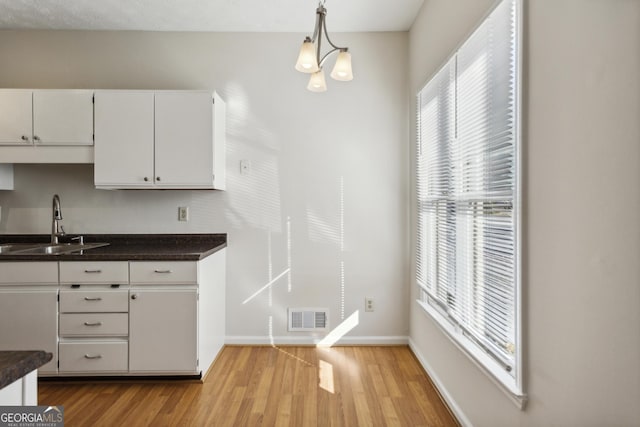 kitchen with sink, decorative light fixtures, a notable chandelier, light hardwood / wood-style floors, and white cabinetry