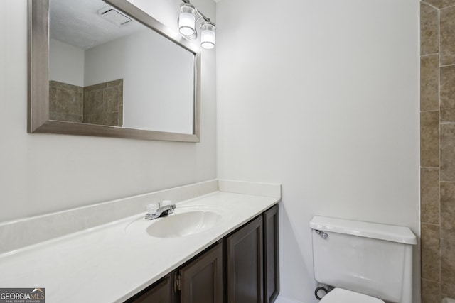 bathroom with a textured ceiling, vanity, and toilet