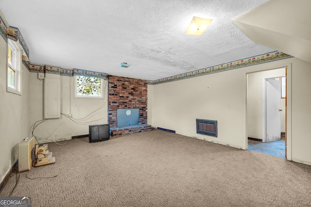 basement with carpet flooring, a textured ceiling, heating unit, and plenty of natural light