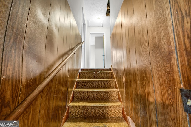 staircase featuring wood walls and a textured ceiling