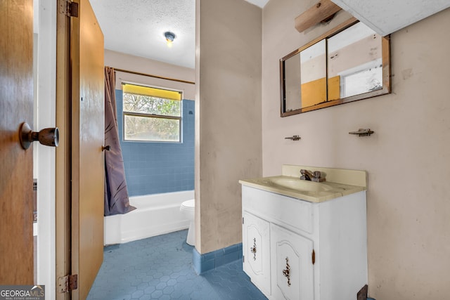 full bathroom with tile patterned floors, a textured ceiling, vanity, toilet, and tiled shower / bath