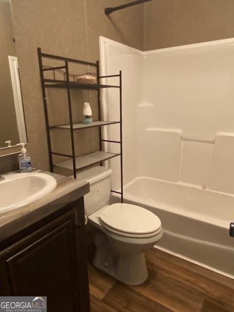 full bathroom with vanity, toilet, wood-type flooring, and tub / shower combination