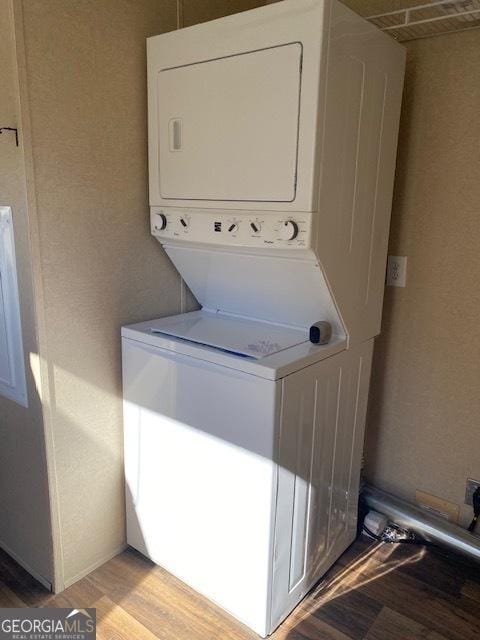 laundry room featuring light hardwood / wood-style flooring and stacked washing maching and dryer