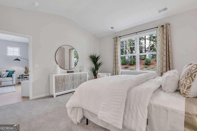 bedroom with light colored carpet and lofted ceiling