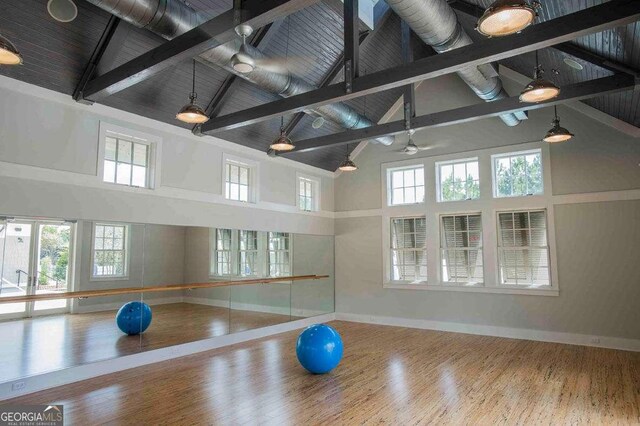 exercise area with hardwood / wood-style floors and high vaulted ceiling