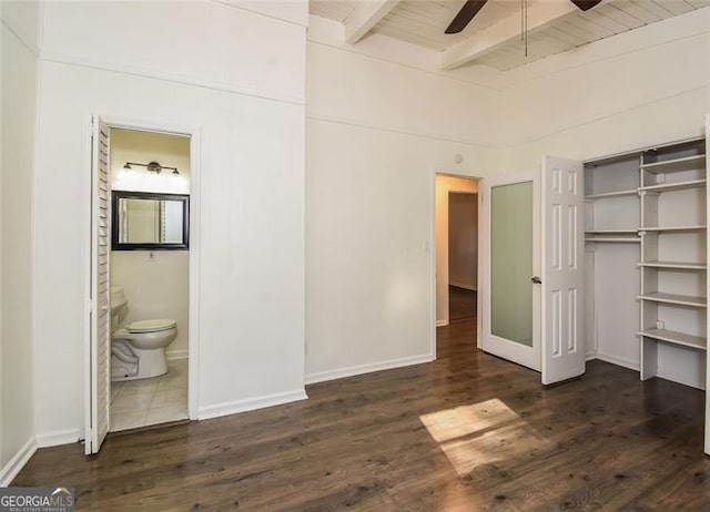 unfurnished bedroom featuring dark hardwood / wood-style flooring, ceiling fan, wooden ceiling, beamed ceiling, and connected bathroom