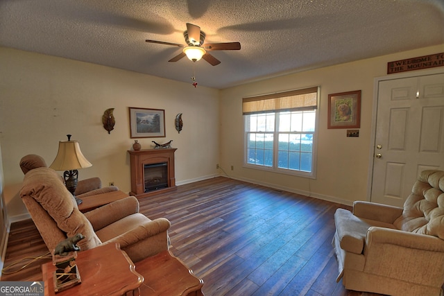 living room with dark wood-type flooring, ceiling fan, and a textured ceiling