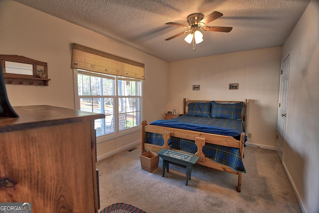 carpeted bedroom featuring ceiling fan and a textured ceiling