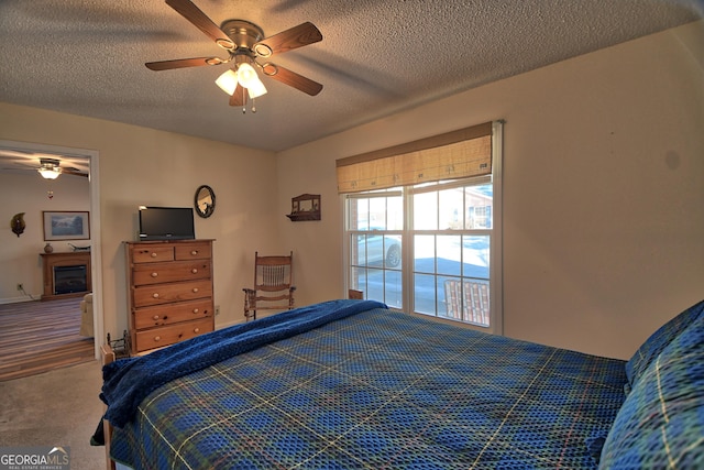 bedroom featuring ceiling fan, a textured ceiling, and carpet flooring