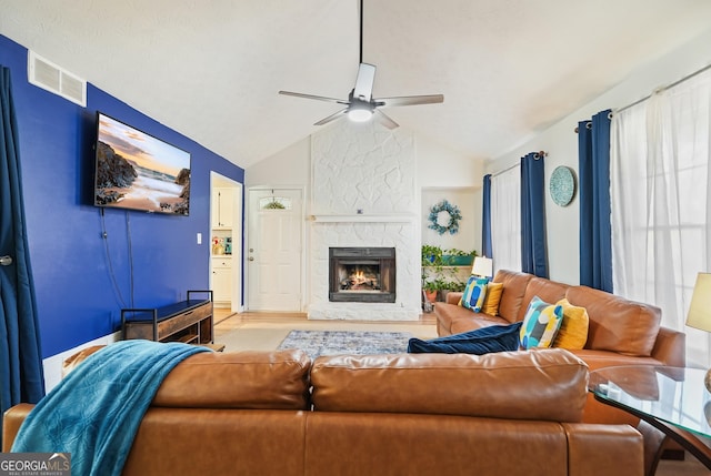 living room with a fireplace, light wood-type flooring, vaulted ceiling, and ceiling fan