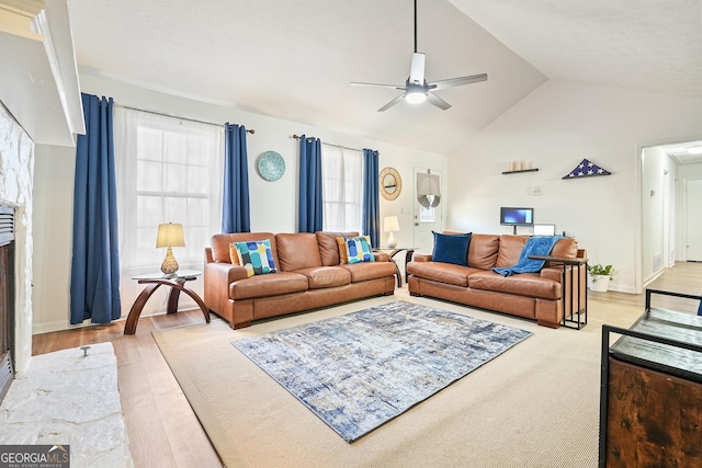 living room with a wealth of natural light, light hardwood / wood-style flooring, ceiling fan, and high vaulted ceiling