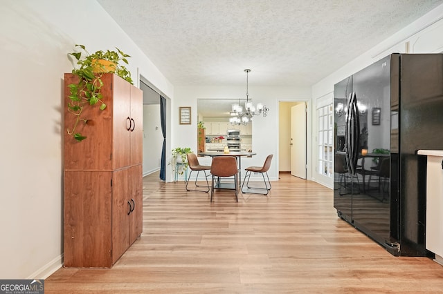 dining room featuring light hardwood / wood-style flooring, a chandelier, and a textured ceiling