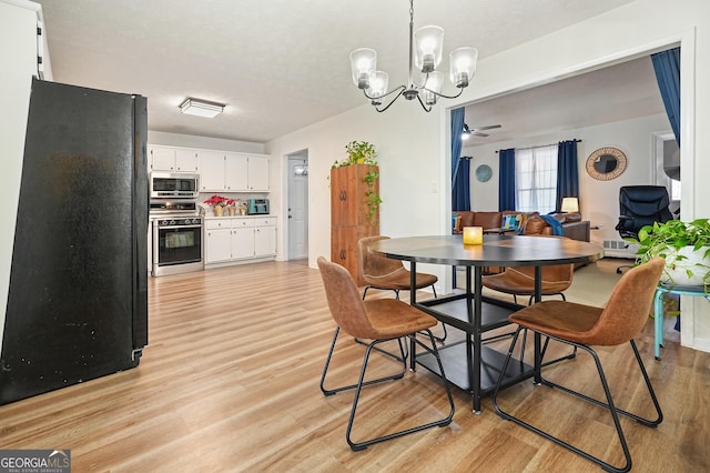 dining room featuring ceiling fan with notable chandelier, light hardwood / wood-style floors, and a textured ceiling