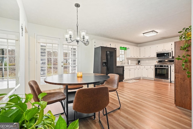 dining room featuring french doors, light wood-type flooring, sink, and an inviting chandelier