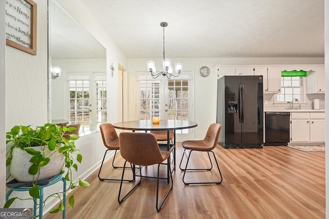 dining room with light hardwood / wood-style floors and an inviting chandelier