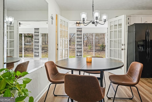 dining area with plenty of natural light, light hardwood / wood-style floors, and ceiling fan with notable chandelier