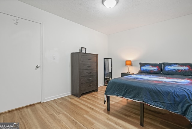 bedroom with a textured ceiling and light hardwood / wood-style flooring