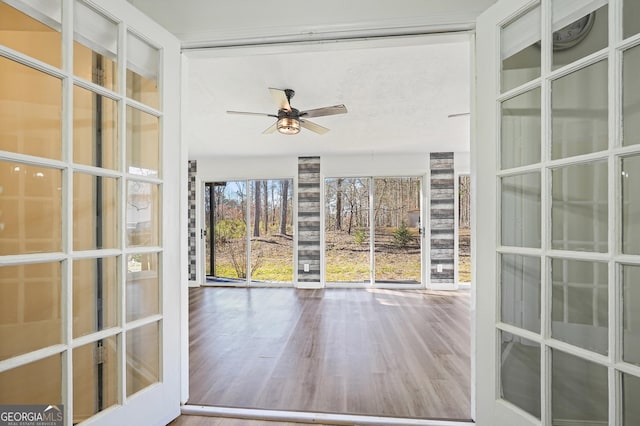 unfurnished sunroom featuring ceiling fan and french doors