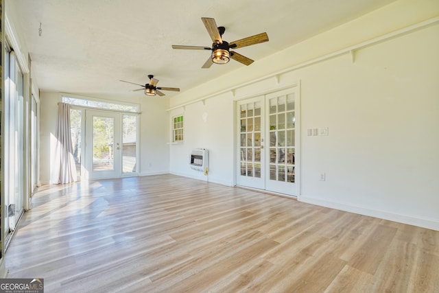 unfurnished sunroom with heating unit, ceiling fan, and french doors