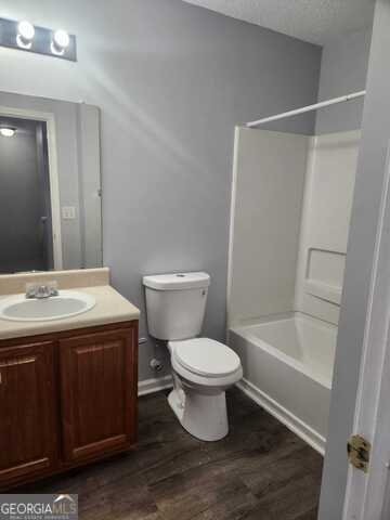 full bathroom with vanity, a textured ceiling, bathing tub / shower combination, hardwood / wood-style flooring, and toilet