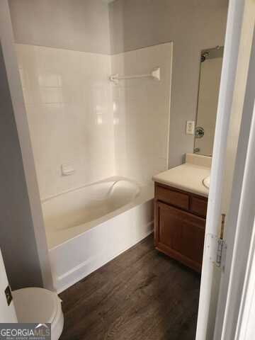 full bathroom featuring hardwood / wood-style floors, vanity, toilet, and shower / washtub combination