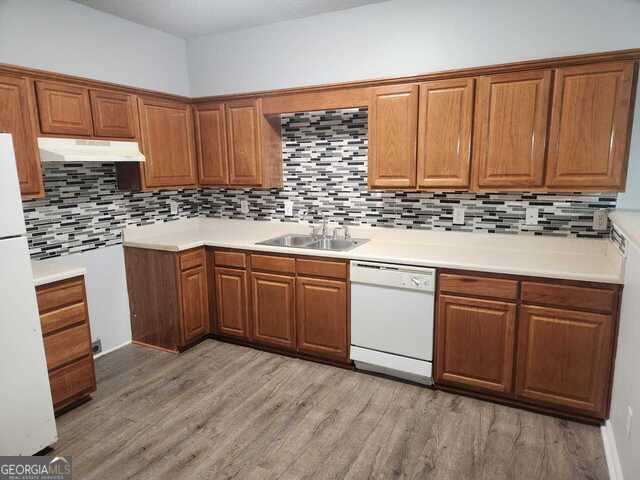 kitchen featuring decorative backsplash, light hardwood / wood-style floors, white appliances, and sink