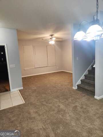 unfurnished living room featuring ceiling fan and dark carpet