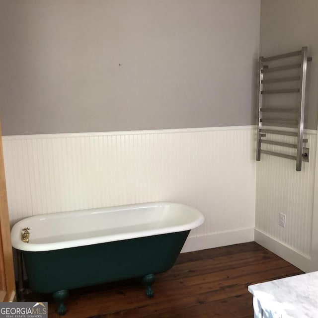 bathroom featuring a washtub, radiator heating unit, and hardwood / wood-style floors