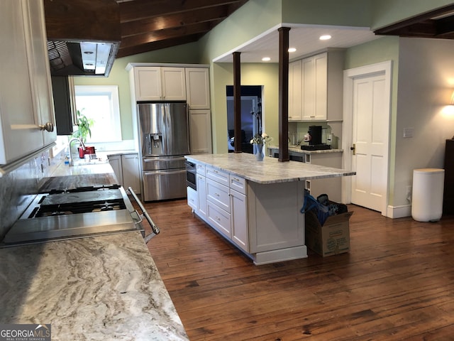 kitchen with a center island, range, sink, stainless steel refrigerator with ice dispenser, and white cabinetry