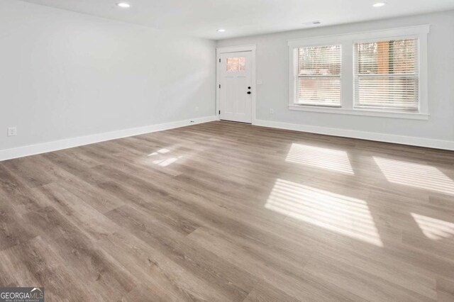 unfurnished living room with baseboards, visible vents, dark wood-style flooring, and recessed lighting