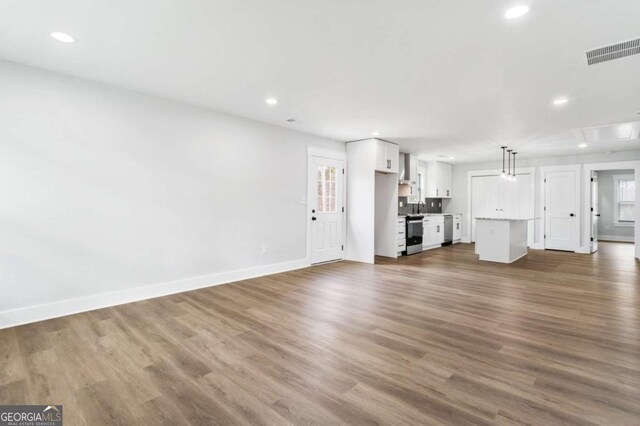 kitchen with electric range, white cabinetry, a sink, wall chimney range hood, and dishwasher