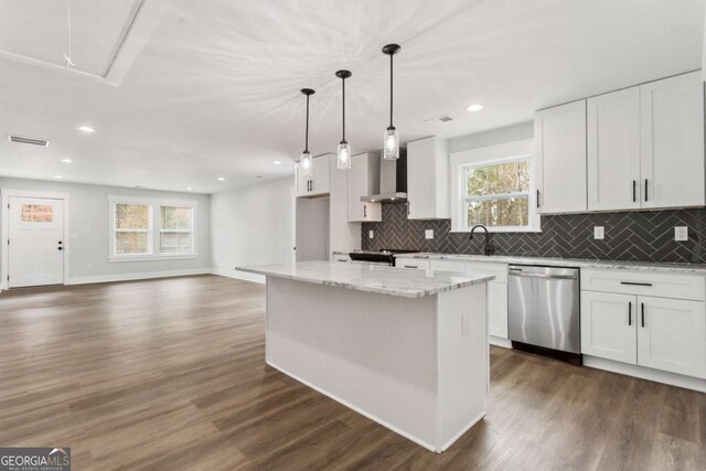 kitchen featuring stainless steel appliances, hanging light fixtures, white cabinetry, a sink, and wall chimney range hood