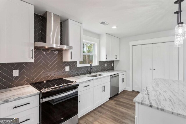 kitchen featuring white cabinetry, stainless steel range with electric stovetop, wall chimney exhaust hood, and light stone counters