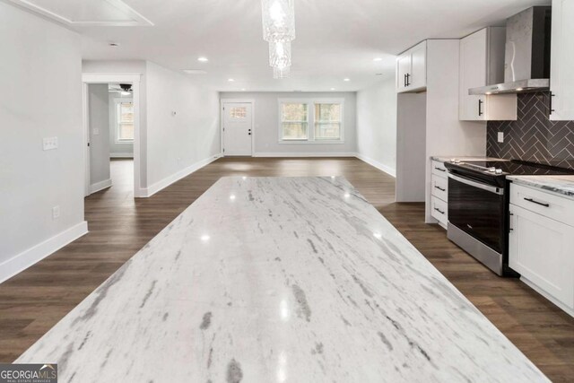 kitchen featuring stainless steel appliances, a kitchen island, white cabinets, wall chimney exhaust hood, and pendant lighting