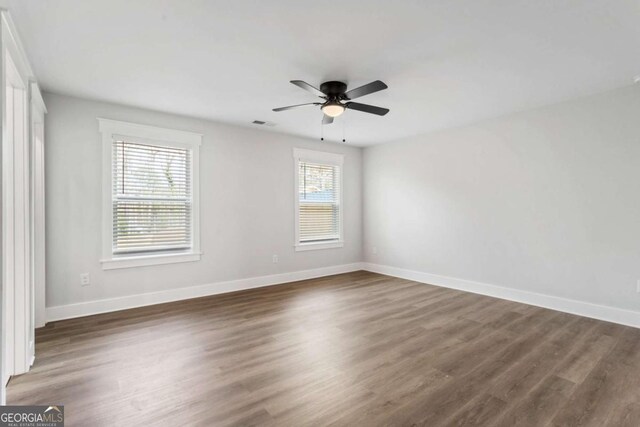 unfurnished bedroom with baseboards, ensuite bath, wood finished floors, a spacious closet, and a closet