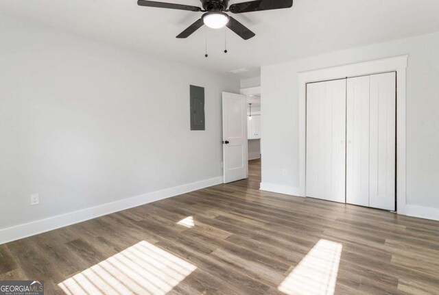 unfurnished bedroom with dark wood-style floors, electric panel, and baseboards