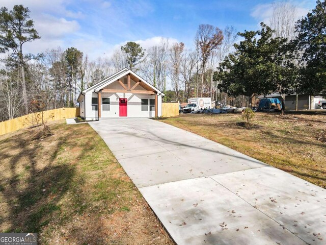 view of front of home with driveway, fence, and a front yard