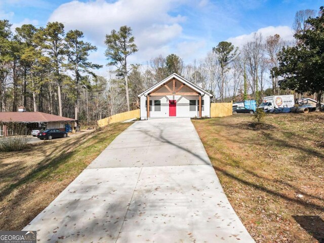 view of front of home featuring driveway, a front lawn, and fence