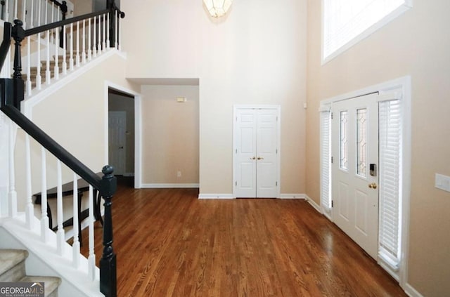 foyer entrance with a towering ceiling and dark wood-type flooring