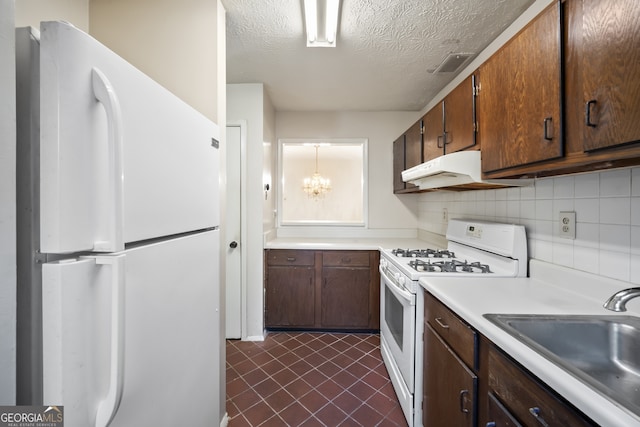 kitchen with decorative backsplash, a textured ceiling, white appliances, sink, and an inviting chandelier