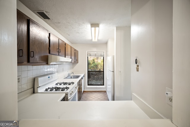 kitchen with white appliances, backsplash, sink, a textured ceiling, and dark brown cabinets